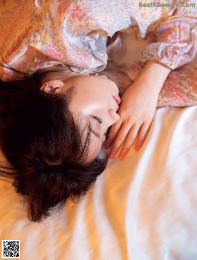 A woman laying on a bed with her eyes closed.