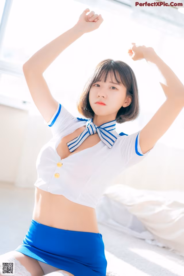 A woman in a white shirt and blue skirt posing for a picture.
