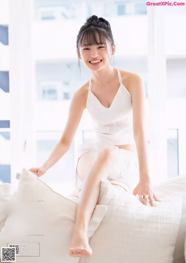 A woman sitting on top of a white couch.