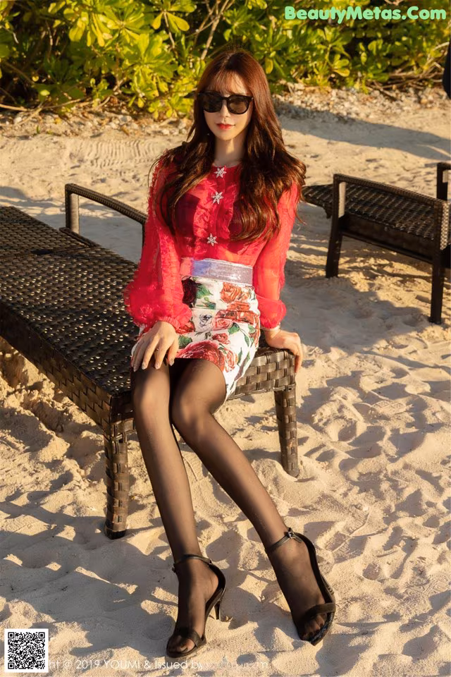 A woman sitting on a bench on the beach.