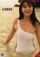 A woman in a white bathing suit standing in the water.