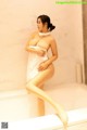 A woman in a bathtub with a towel wrapped around her body.