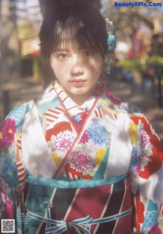 A woman in a colorful kimono poses for a picture.