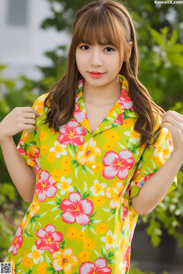 A woman in a yellow and pink floral dress posing for a picture.