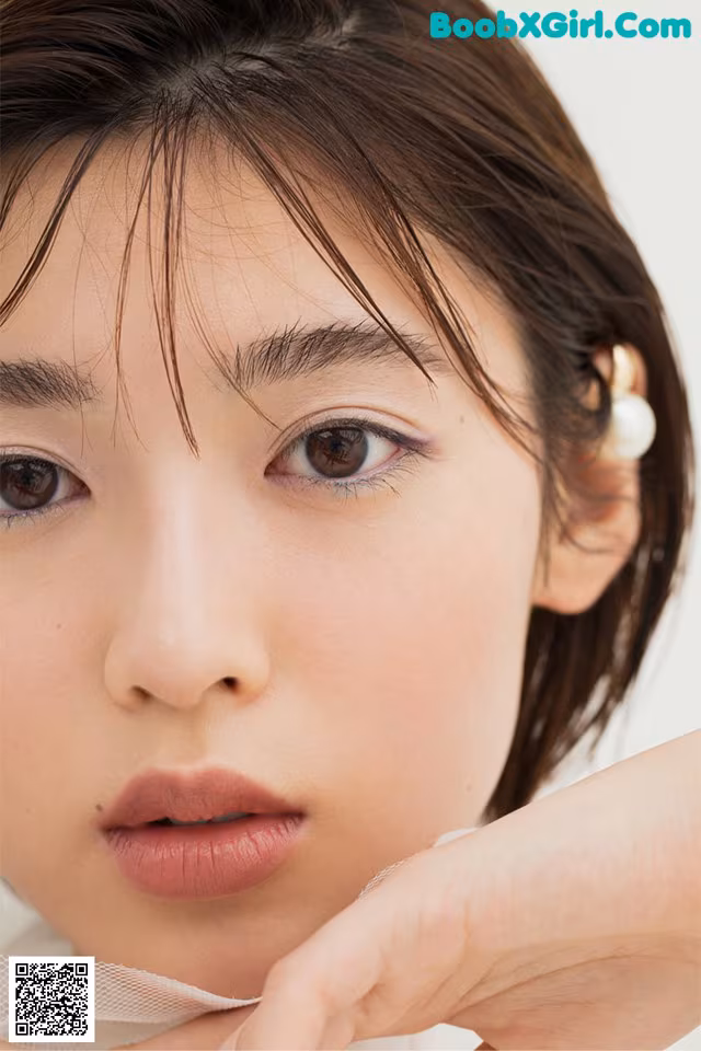 A close up of a woman's face with a pearl earring.