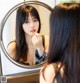 A woman applying lipstick in front of a mirror.