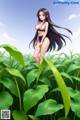 A woman in a bikini standing in a field of green plants.