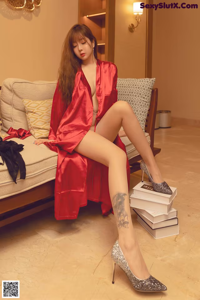 A woman in a red robe sitting on a couch.