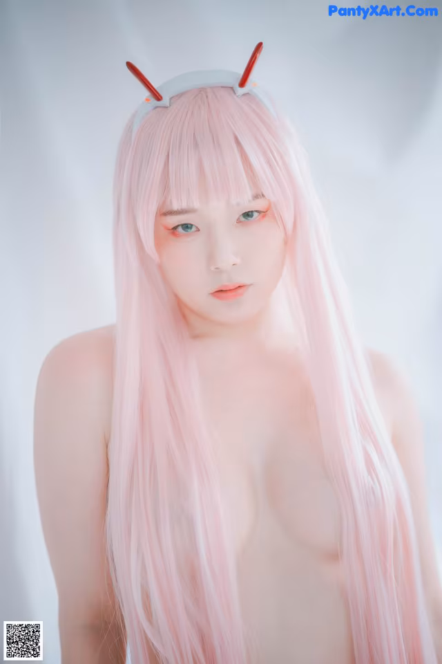 A woman with long pink hair wearing a devil horns headband.