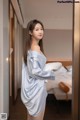 A woman in a blue robe standing in a hotel room.