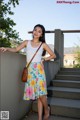 A woman in a white tank top and a colorful skirt.