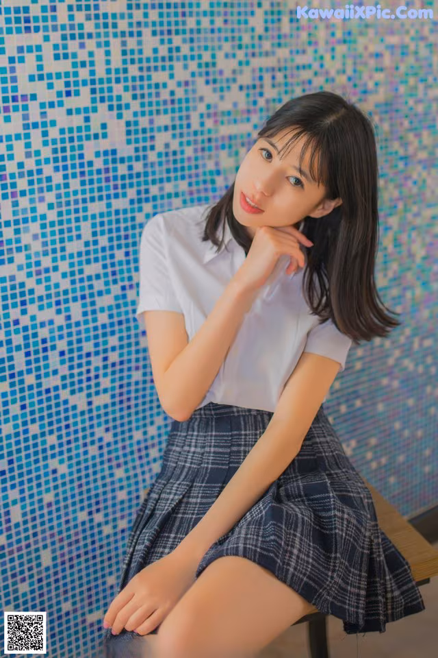 A woman in a school uniform sitting on a bench.