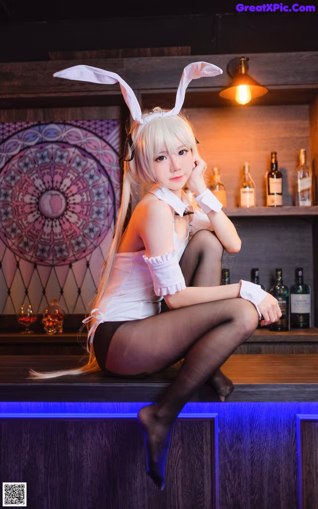 A woman in a bunny costume sitting on a bar.