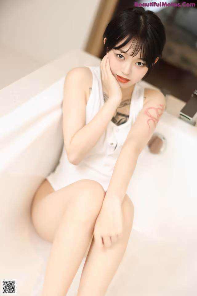 A woman sitting in a bathtub with her legs crossed.