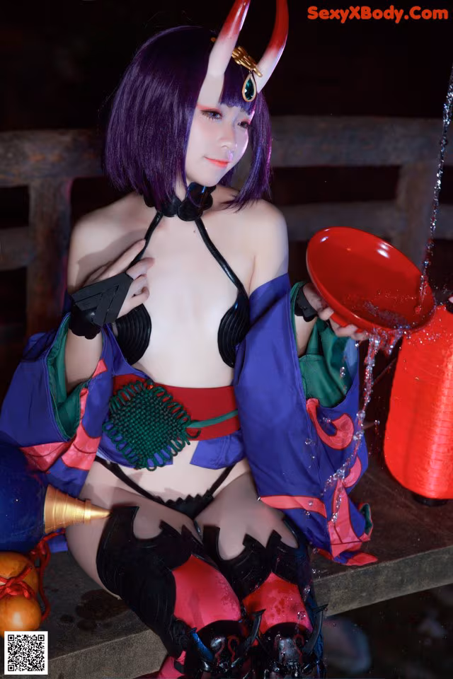 A woman dressed as a demon holding a red bowl.